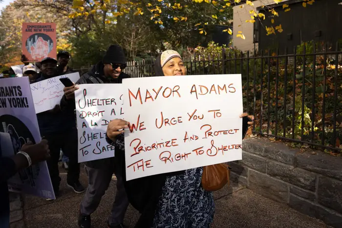 Demonstrators hold signs outside of Gracie Mansion urging the mayor to protect the right to shelter o